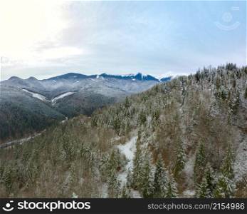 The mountains are covered with forest. The first snow on the ground and branches. Overcast. Aerial view. Beginning of Winter in the Mountains. Aerial View