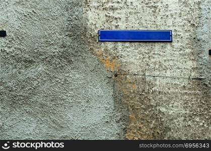 the nameplate on the house on the street, a sign on the stone wall outside on the street