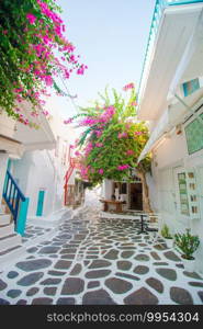 The narrow streets of the island with blue balconies, stairs and flowers.. Beautiful architecture building exterior with cycladic style in greek village