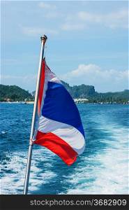 The national flag of thailand on the stern of the boat and the view of the wake