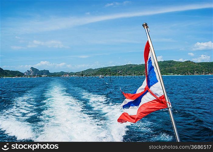 The national flag of thailand on the stern of the boat and the view of the wake
