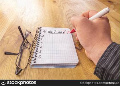 The new year, 2017, to do list concept, written by a man s hand with a marker on a mathematics spiral notebook. Conceptual image for planning and organizing.