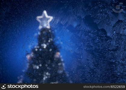 The New Year tree image behind frosty glass. Fur-tree
