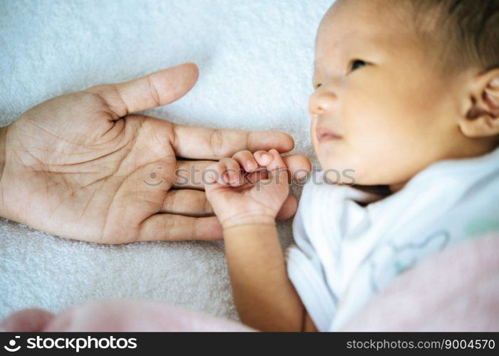 The newborn baby opens his eyes and puts the hand on the mother&rsquo;s hand