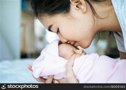 The newborn baby sleeping in the mother’s arms and fragrant on the baby’s forehead.