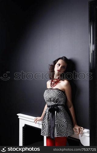 The nice girl in a dress and red stockings at a wall