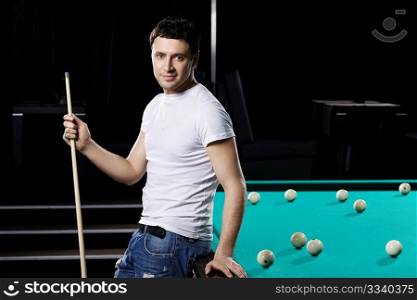 The nice young man with cue at a billiard table