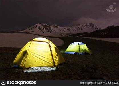 The night before the ascent - the tents of tourists shine at the foot of Erciyes Dag in central Anatolia, Turkey.. Tents of tourists are located at the foot of Mount Erciyes in central Turkey
