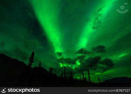 The Northern Lights emerge through the clouds in remote Alaska