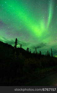 The Northern Lights emerge through the clouds in remote Alaska