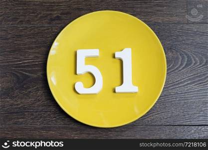The number fifty-one on the yellow plate and brown background.. The number fifty-one on the yellow plate.