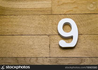 The number nine on wooden parquet floor in the background.. The figures are nine on the wooden, parquet floor.