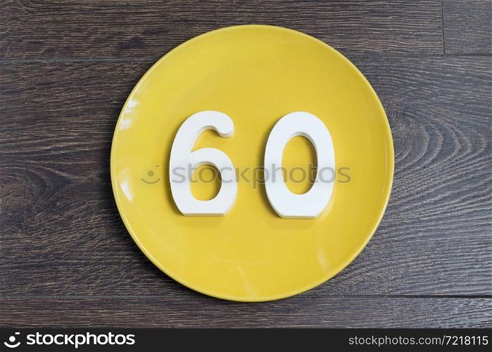The number sixty on the plate yellow and brown background.. The number sixty on the yellow plate.