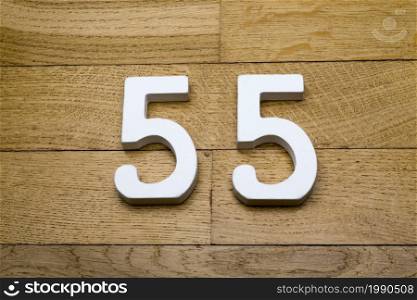 The numbers fifty-five on the wooden parquet floor in the background.. The numbers fifty-five on a wooden parquet floor.