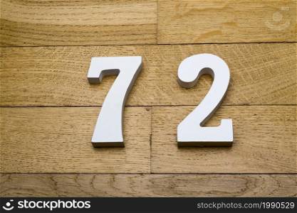 The numbers seventy-two on the wooden parquet floor in the background.. The numbers seventy-two on the wooden parquet floor.