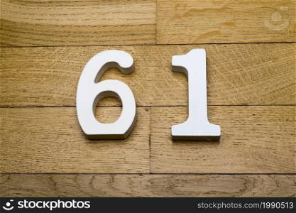 The numbers sixty-one on the wooden parquet floor in the background.. The numbers sixty-one on the wooden parquet floor.