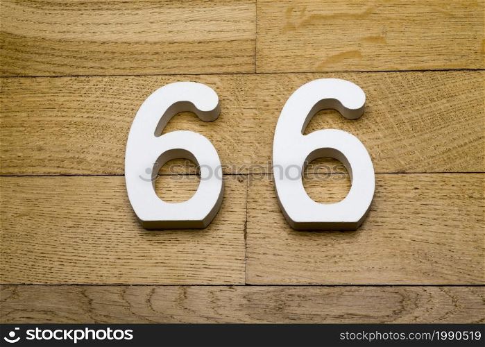 The numbers sixty-six on wooden parquet floor in the background.. The numbers sixty-six on a wooden parquet floor.