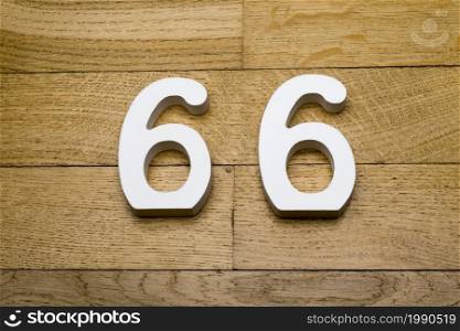 The numbers sixty-six on wooden parquet floor in the background.. The numbers sixty-six on a wooden parquet floor.