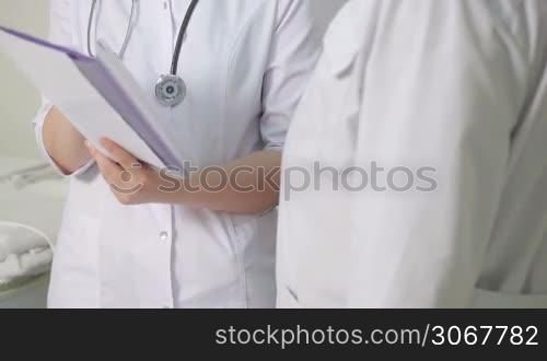 The nurse reported to the doctor about medical tests. Panning shot. Close up.