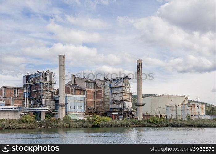 The old chemical factory with chimneys and silo on the banks of the river