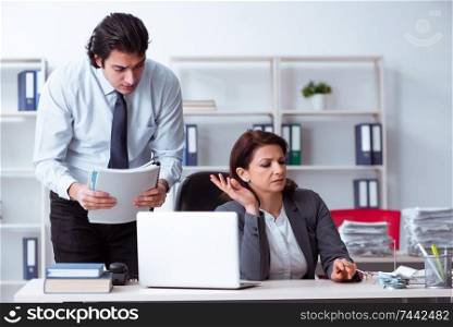 The old female boss and young male employee in the office  . Old female boss and young male employee in the office  