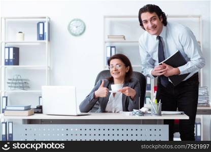 The old female boss and young male employee in the office. Old female boss and young male employee in the office