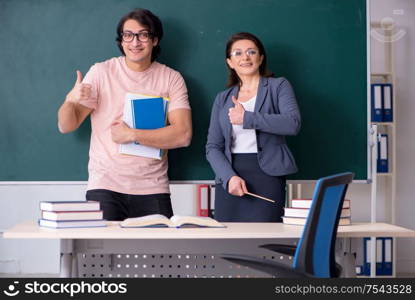 The old female teacher and male student in the classroom. Old female teacher and male student in the classroom