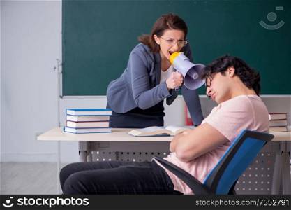 The old female teacher and male student in the classroom. Old female teacher and male student in the classroom