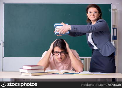 The old female teacher and male student in the classroom. Old female teacher and male student in the classroom