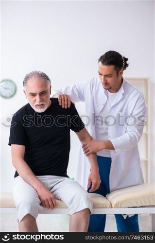 The old injured man visiting young doctor . Old injured man visiting young doctor 