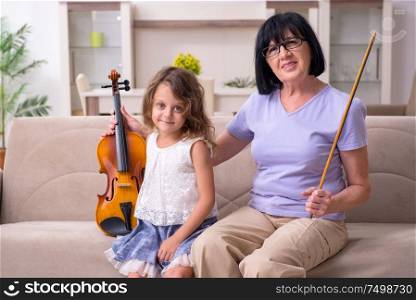 The old lady teaching little girl to play violin. Old lady teaching little girl to play violin