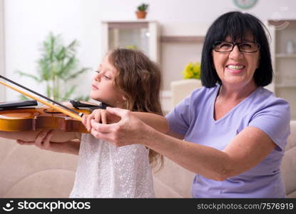 The old lady teaching little girl to play violin. Old lady teaching little girl to play violin