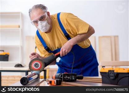 The old male carpenter working in workshop . Old male carpenter working in workshop