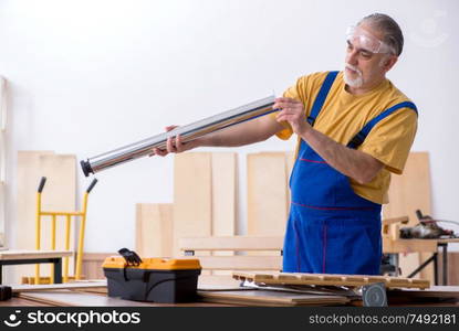 The old male carpenter working in workshop. Old male carpenter working in workshop