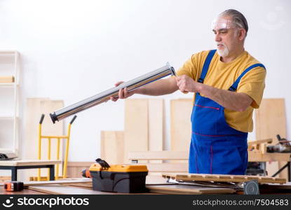 The old male carpenter working in workshop. Old male carpenter working in workshop