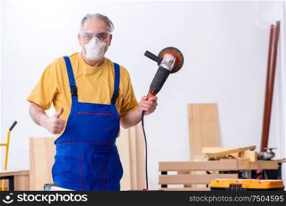 The old male carpenter working in workshop. Old male carpenter working in workshop