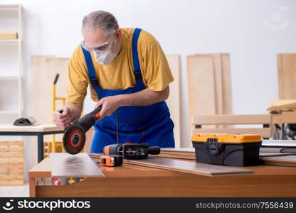 The old male carpenter working in workshop. Old male carpenter working in workshop