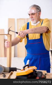 The old male carpenter working in workshop. Old male carpenter working in workshop