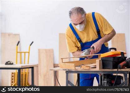 The old male carpenter working in workshop. Old male carpenter working in workshop