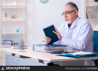 The old male doctor working in the clinic . Old male doctor working in the clinic 