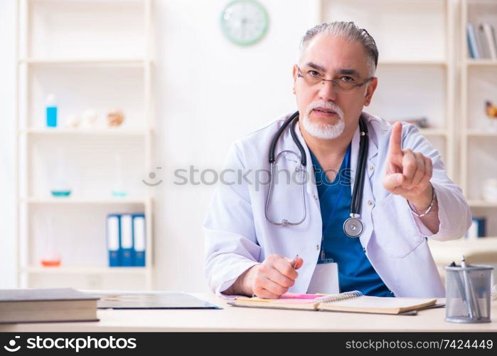 The old male doctor working in the clinic . Old male doctor working in the clinic 