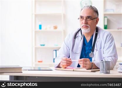 The old male doctor working in the clinic . Old male doctor working in the clinic 