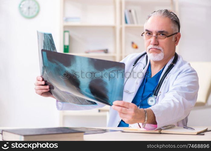 The old male doctor working in the clinic . Old male doctor working in the clinic 