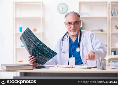 The old male doctor working in the clinic . Old male doctor working in the clinic