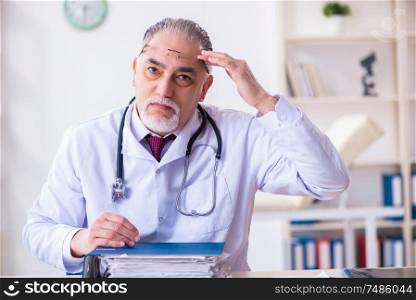 The old male doctor working in the clinic . Old male doctor working in the clinic