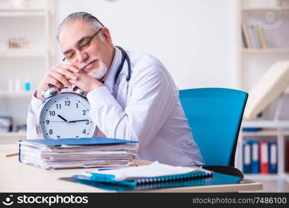 The old male doctor working in the clinic . Old male doctor working in the clinic