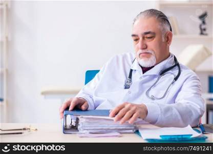 The old male doctor working in the clinic. Old male doctor working in the clinic