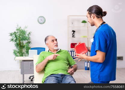 The old man visiting young male doctor gastroenterologist. Old man visiting young male doctor gastroenterologist