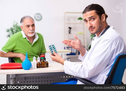 The old man visiting young male doctor gastroenterologist. Old man visiting young male doctor gastroenterologist