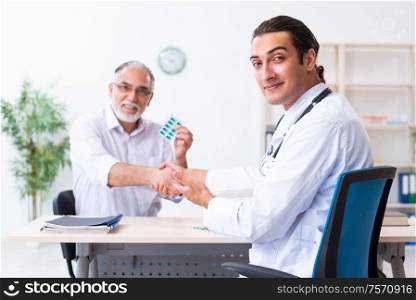 The old man visiting young male doctor. Old man visiting young male doctor